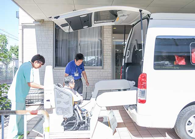 送迎車から車椅子に乗る利用者を降ろす様子